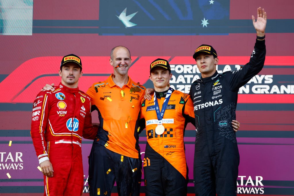 Charles Leclerc, Scuderia Ferrari, 2nd position, the McLaren trophy delegate, Oscar Piastri, McLaren F1 Team, 1st position, George Russell, Mercedes-AMG F1 Team, 3rd position, on the podium
