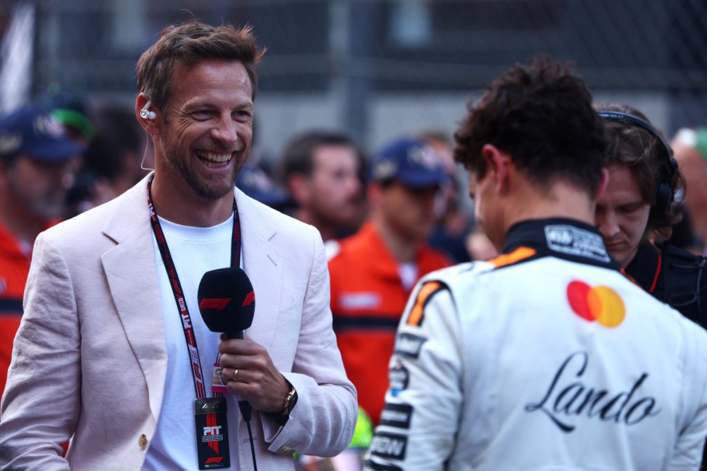 Jenson Button smiles while interviewing race winner Lando Norris on the grid.