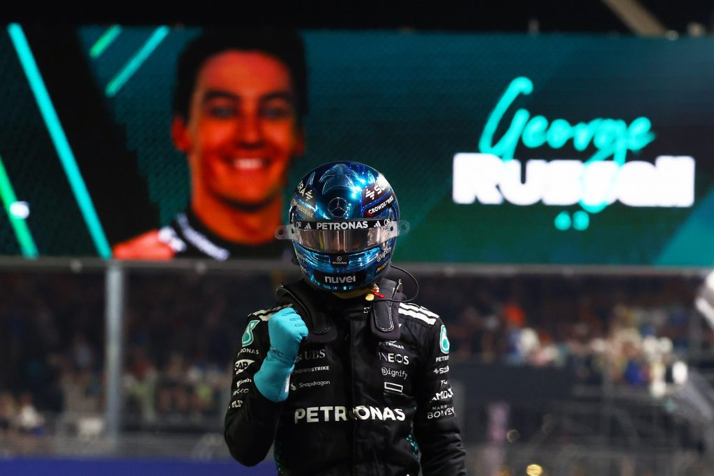 George Russell celebrating pole position at the 2025 F1 Singapore Grand Prix , Mercedes driver raising his fist in front of big screen.
