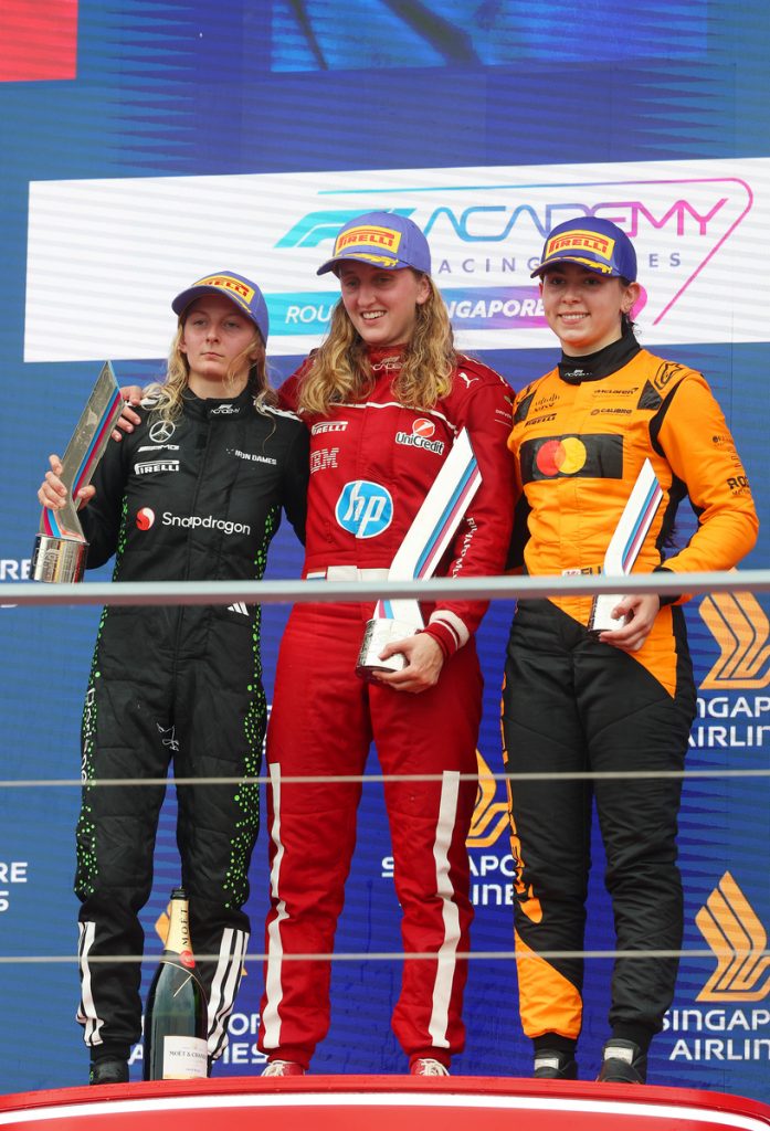 F1 Academy podium in Singapore: Maya Weug celebrates victory alongside runners-up on the rostrum, holding trophies after another dominant weekend.