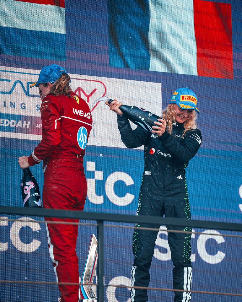 Maya Weug and Doriane Pin spraying champagne on the podium after an F1 Academy race.