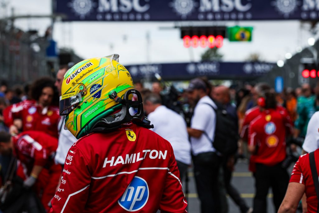 Hamilton in Ferrari race suit wearing Brazil-themed helmet on the São Paulo grid during 2025 F1 Brazilian Grand Prix weekend.