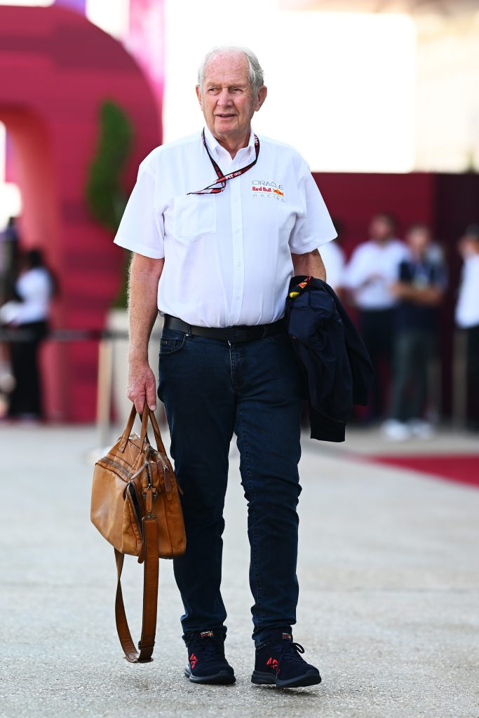 Helmut Marko walks through the Formula 1 paddock wearing Red Bull team clothing during the 2025 season.